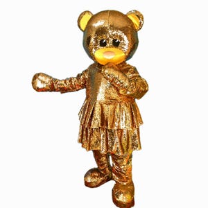 Disfraz de mascota osito de peluche dorado con vestido. Mascot World Corporation ofrece producción de disfraces de mascota ecológicos. Disfraces de mascota personalizados