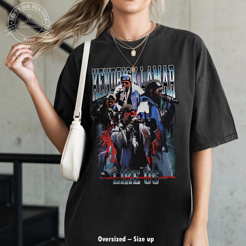 Op de afbeelding: Zwart oversized T-shirt met een vintage-stijl grafische afbeelding van Kendrick Lamar en de tekst "Kendrick Lamar" en "To Pimp a Butterfly Like Us".