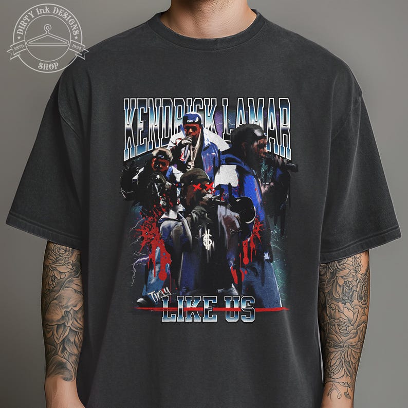 Op de afbeelding: Zwart T-shirt met een vintage-stijl afbeelding van Kendrick Lamar en de woorden "They Like Us".