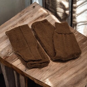 May include: Two pairs of brown knitted socks, one pair folded and one pair laid flat on a wooden surface.