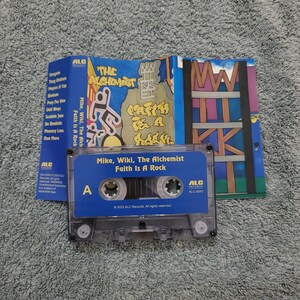 May include: A blue cassette tape with the title "Mike, Wiki, The Alchemist Faith Is A Rock" printed on the front. The tape is labeled with the letter "A" and the text "2023 ALC Records. All rights reserved."