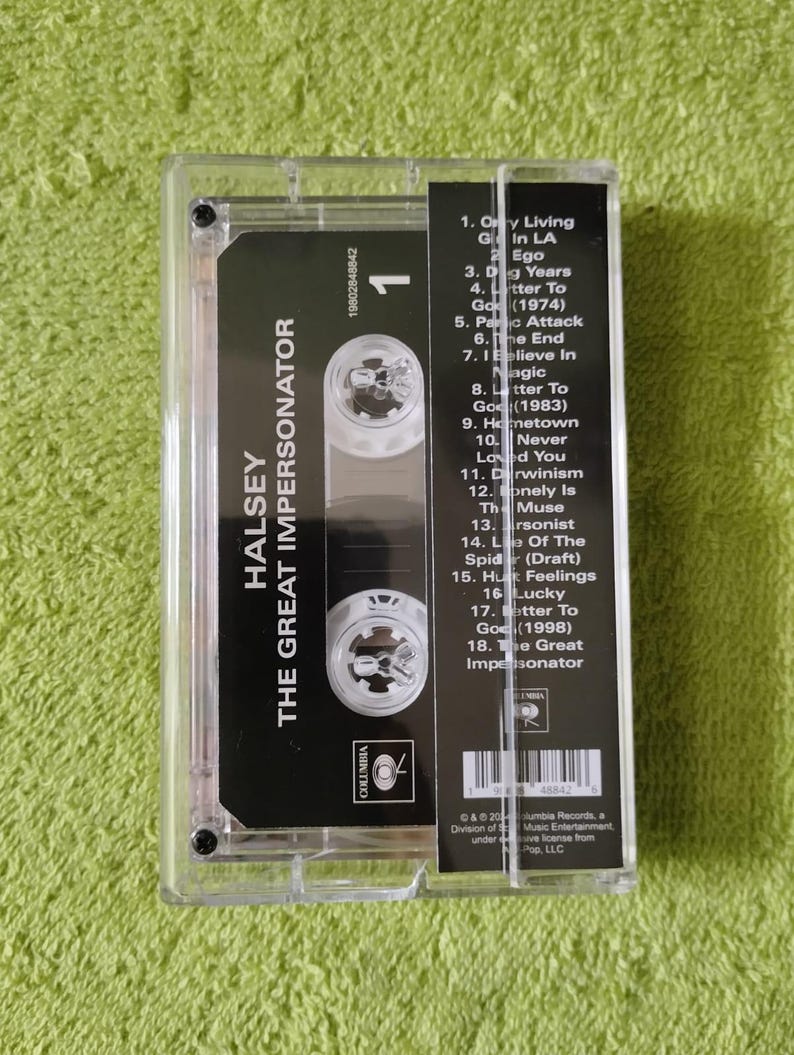 May include: A clear cassette tape case containing a black cassette tape with the album title "The Great Impersonator" by Halsey. The cassette label includes a tracklist and the Columbia Records logo.