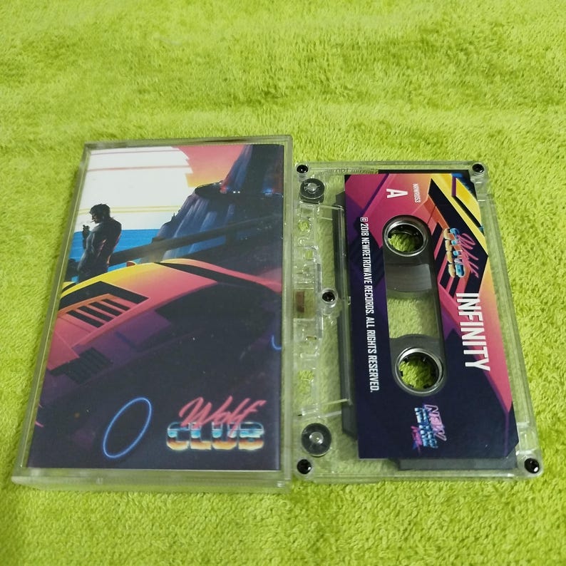May include: A clear cassette tape with a pink, blue, and black design. The tape features the text "Wolf Club" and "Infinity".