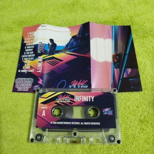 May include: A cassette tape with a pink, blue, and black design. The tape has the words "Wolf Club" and "Infinity" on it. The cassette tape is in a clear plastic case.