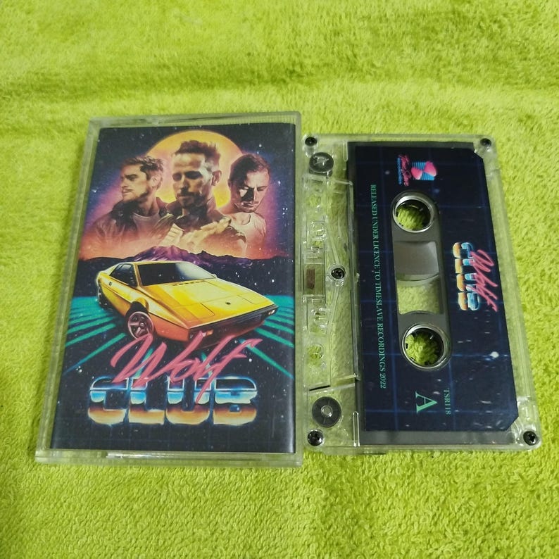 May include: A cassette tape with a retro design featuring a yellow sports car and three men. The cassette tape is labeled "Wolf Club" and "Released under licence to Timeslave Recordings 2022".