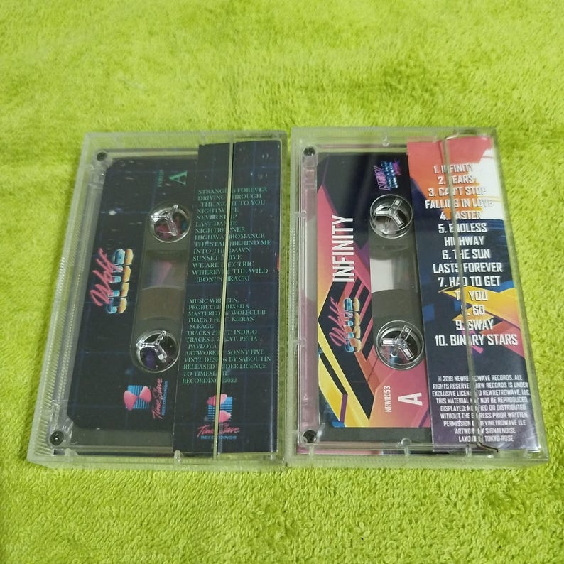 May include: Two cassette tapes with a black and white design. The tape on the left has the text "Club" and the tape on the right has the text "Infinity". Both tapes have a side A label.