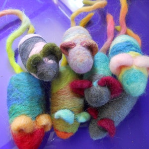 May include: Five colorful felt mice toys with long tails. The mice are made of different colors of felt, including blue, green, pink, gray, and yellow. The mice have different facial features, including black eyes and pink noses.