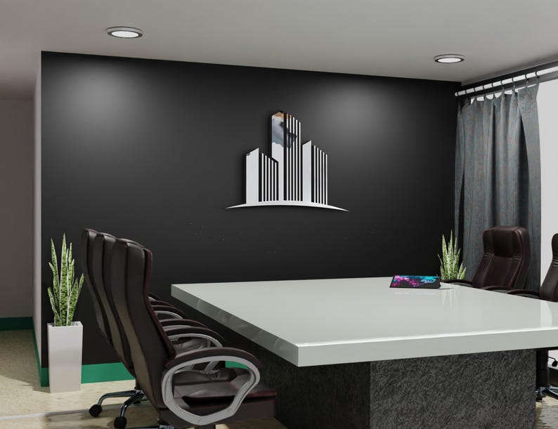 May include: A modern office setting featuring a large white conference table with a dark gray base. Black leather office chairs surround the table. A stylized building logo is mounted on the black wall. Green plants and gray curtains add to the decor.