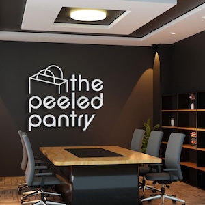 May include: An office interior featuring a conference table, chairs, and a bookshelf. The wall displays the logo "the peeled pantry" in white lettering. The room has a modern design with neutral colors and recessed lighting.