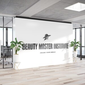 May include: Interior shot of a modern office space with the words "BEAUTY MASTER INSTITUTE" in metallic lettering on a white wall. A logo of a woman in a hat is above the text. The phrase "CHASE YOUR DREAM" is below the text.