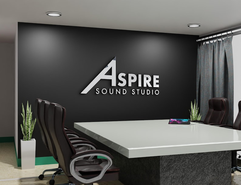 May include: A modern conference room with a large white table and black leather chairs. The wall features the text "ASPIRE SOUND STUDIO" in silver lettering. Two potted plants and a tablet are on the table.