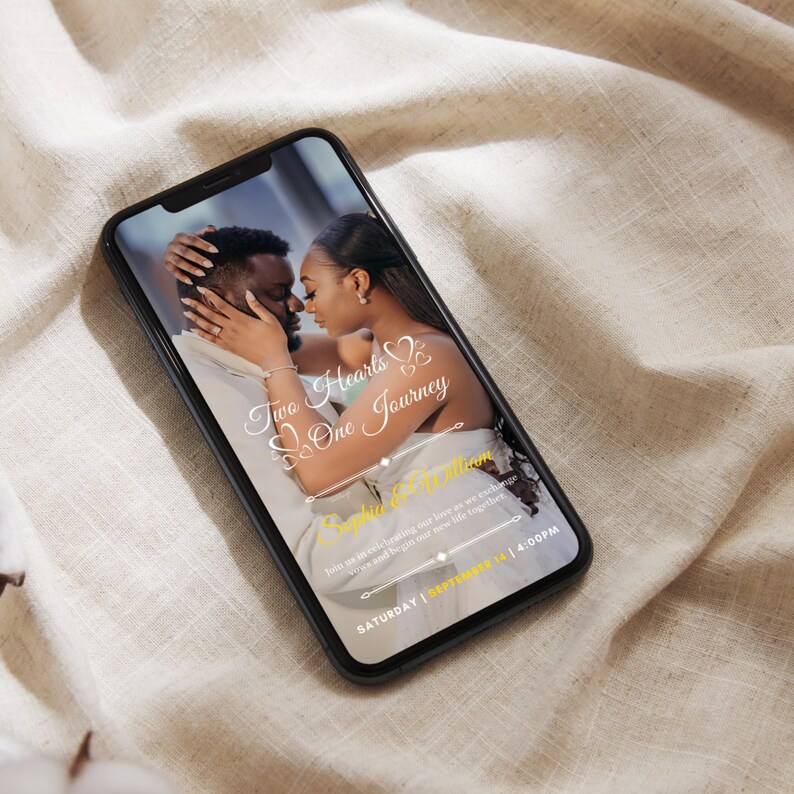May include: A smartphone screen shows a wedding invitation featuring a couple's photo. The text says "Two Hearts, One Journey", the names "Sophia & William", and the date "SATURDAY | SEPTEMBER 14 | 4:00PM". The phone is on a beige fabric.