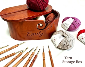 Könnte beinhalten: Eine hölzerne Garnaufbewahrungsbox mit Deckel, personalisiert mit dem Namen "Emily". Die Box ist mit verschiedenen Garnfarben gefüllt und von Häkelnadeln und Garnknäueln umgeben. Der Text "Yarn Storage Box" ist sichtbar.
