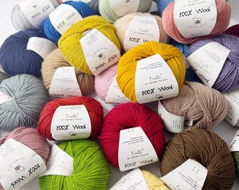 Könnte beinhalten: Eine Sammlung bunter Wollknäuel in verschiedenen Farbtönen, darunter Gelb, Rot, Grün, Blau und Rosa. Jedes Knäuel trägt ein Etikett mit der Aufschrift "100% Wolle". Die Wolle ist in einem ansprechenden, verstreuten Muster angeordnet.