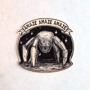 Könnte beinhalten: Ein schwarz-weißer Aufkleber mit einem stilisierten insektenartigen Wesen und dem Wort "AMAZE" in einem Banner. Das Design umfasst einen Sternenhintergrund und eine strukturierte Optik.