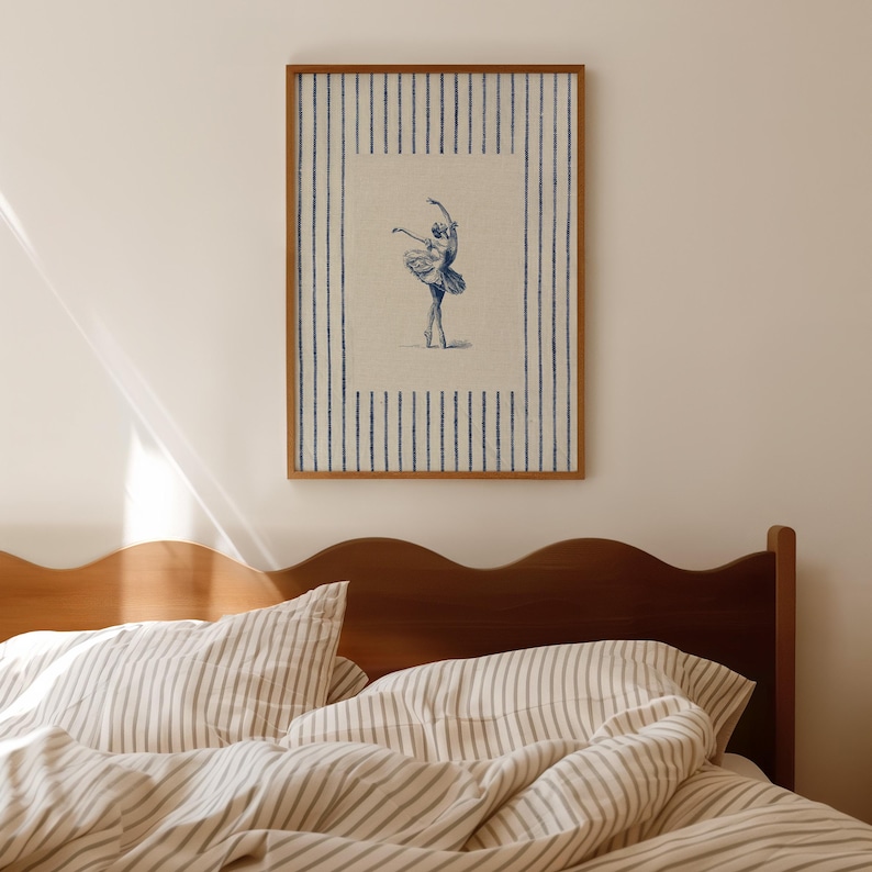 May include: A framed rectangular wall art print featuring a central illustration of a ballet dancer in a tutu, rendered in blue ink on a cream background. The print is surrounded by a border of vertical blue stripes on a cream-colored field.