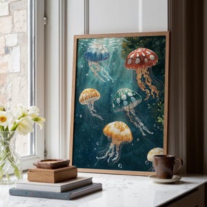 May include: A framed wall art print featuring five jellyfish in shades of blue, red, green, and orange swimming in deep teal water. The jellyfish have translucent bells with white spots and long, flowing tentacles. The print is in a light wood frame.