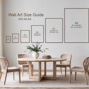 May include: A wall art size guide chart labeled ISO A0-A5 with six rectangular frames showing dimensions in inches and centimeters, ranging from A5 to A0, displayed above a round light wood dining table with four matching woven chairs.