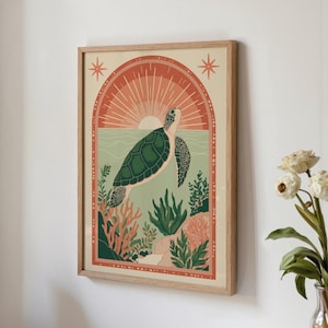 May include: A framed art print featuring a green sea turtle swimming in the ocean. The artwork has a retro style with a sunset and coral reef in the background. The frame is made of light-colored wood.