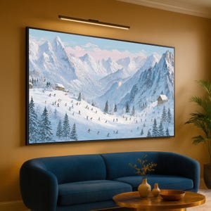 Könnte beinhalten: Ein großes, gerahmtes Gemälde zeigt eine schneebedeckte Berglandschaft mit Skifahrern. Das Kunstwerk in einem schwarzen Rahmen hängt über einem blauen Sofa und einem runden Holztisch. Über dem Gemälde ist eine schwarze Leuchte angebracht.