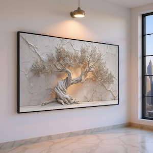 Op de afbeelding: Een groot, ingelijst kunstwerk aan de muur met een getextureerd, driedimensionaal reliëf van een boom. Het kunstwerk is voornamelijk gebroken wit en beige, met een zwart frame. De stam van de boom is knoestig en gedraaid, met delicate takken en bladeren.