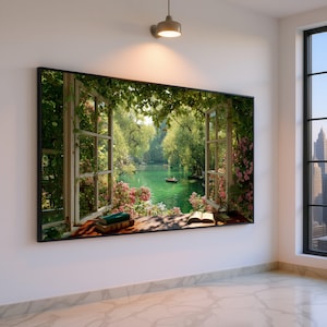 Puede incluir: Una gran obra de arte enmarcada representa una ventana abierta con vistas a un lago sereno. El marco de la ventana es blanco, con exuberante vegetación y flores rosas que enmarcan la vista. Dos libros descansan en el alféizar. La obra está montada en una pared blanca.