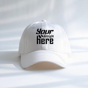 Könnte beinhalten: Eine weiße Baseballkappe mit gebogenem Schirm. Auf der Kappe steht in schwarzer, stilisierter Schrift der Text "Your design here". Der Hut ist aus glattem Stoff gefertigt und hat einen Knopf oben.