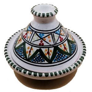 May include: A white ceramic tagine pot with a conical lid and a round base. The lid features a geometric pattern in black, green, blue, orange, and red. The rim of the base and the lid's top are trimmed with green. A traditional cooking pot.