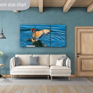 May include: A three-panel canvas print of a duck in water, with its wings spread. The artwork is displayed above a white sofa in a living room setting. The text "Livingroom size chart" is in the upper left corner.