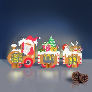 May include: A festive Christmas train set with three connected cars. The first car features Santa Claus, the second a Christmas tree and gifts, and the third a snowman and reindeer. Each car has red wheels and is decorated with holiday-themed elements.