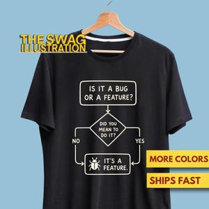 May include: A black short-sleeved t-shirt featuring a white graphic flowchart. The text reads: IS IT A BUG OR A FEATURE? DID YOU MEAN TO DO IT? NO or YES. The final box says: IT'S A FEATURE with a small bug icon. The shirt hangs on a wooden hanger.