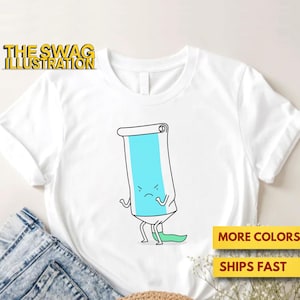 Op de afbeelding: Wit T-shirt met een cartoon illustratie van een boze tube tandpasta. De tube is lichtblauw met zwarte contouren en heeft armen en benen. De tekst "THE SWAG ILLUSTRATION" staat in de linkerbovenhoek.