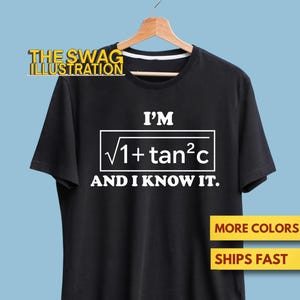 Puede incluir: Camiseta negra con el texto blanco "I'M √1+tan²c AND I KNOW IT.". La camiseta está colgada de una percha de madera sobre un fondo azul claro. La esquina superior izquierda tiene el texto "THE SWAG ILLUSTRATION".