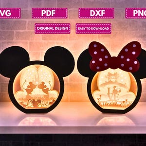 Könnte beinhalten: Zwei beleuchtete Lampen in Form von Mickey und Minnie Mouse. Eine hat Mickys Ohren, die andere Minnie's Schleife. Jede Lampe hat ein ausgeschnittenes Design mit einer romantischen Szene im Inneren und dem Wort "Love".