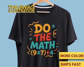 May include: Black t-shirt with the text "DO THE MATH (9x7)+4" in orange, red, and teal. The shirt is hanging on a wooden hanger against a light blue background. The words "MORE COLORS" and "SHIPS FAST" are also visible.