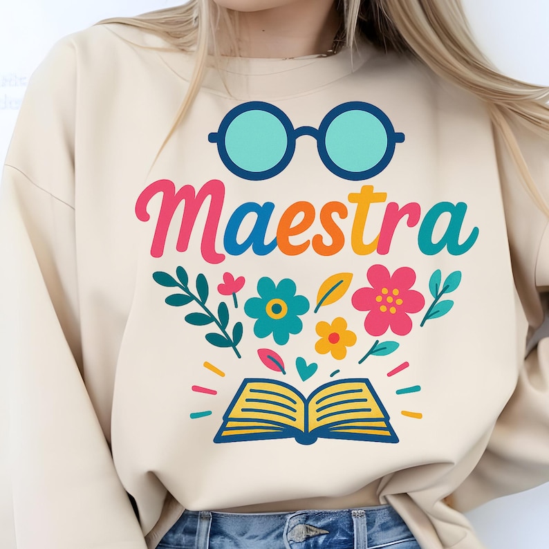 Puede incluir: Sudadera beige con la palabra "Maestra" en letras coloridas, con gafas, flores y un gr&aacute;fico de libro abierto. El dise&ntilde;o incluye elementos turquesa, rosa, naranja, amarillo y verde. Dise&ntilde;o tem&aacute;tico de profesor.