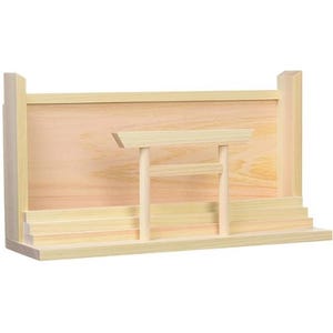 May include: A light-colored wooden Shinto altar shelf featuring a stepped base and a vertical back panel. A small, detached wooden torii gate stands in the center of the platform, positioned in front of the back panel with two vertical posts.