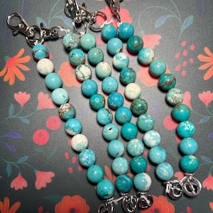 May include: Four turquoise and white beaded keychains with silver charms. Each keychain has a silver lobster clasp.