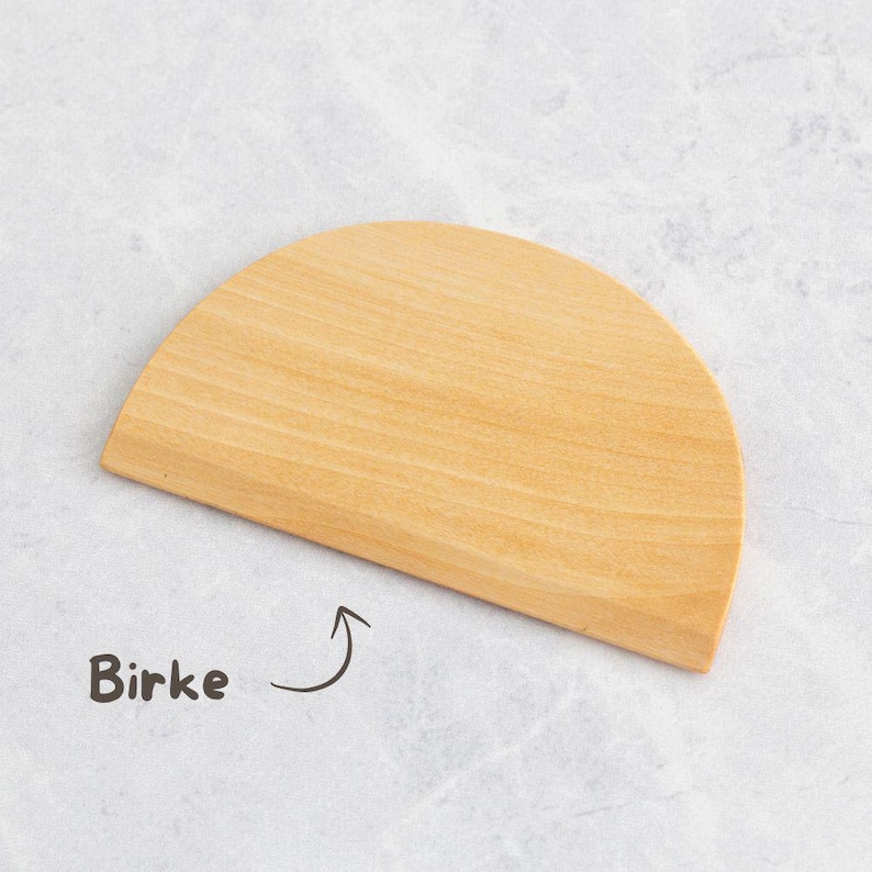 K&ouml;nnte beinhalten: Ein helles, halbkreisf&ouml;rmiges Schneidebrett aus Holz. Das Wort "Birke" ist in einer handschriftlichen Schriftart in der N&auml;he des Bretts geschrieben. Das Brett hat eine glatte Oberfl&auml;che und ein nat&uuml;rliches Holzmaserungsmuster.