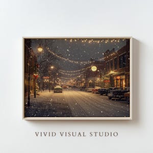 May include: A snowy, nighttime scene of a street lined with brick buildings decorated with Christmas lights. Cars are parked along the street, and snow is falling gently.
