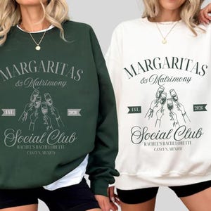 May include: Two sweatshirts, one dark green and one white, with the text "MARGARITAS & Matrimony Social Club" in a script font. The design includes an illustration of hands toasting glasses and the text "RACHEL'S BACHELORETTE CANCUN, MEXICO".