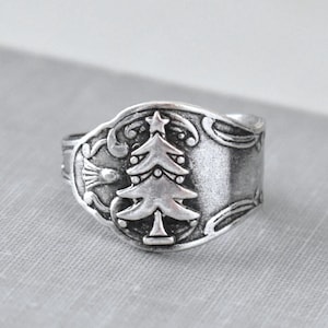 May include: Silver ring with a Christmas tree design. The ring is made from a repurposed spoon.