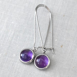 May include: A pair of silver dangle earrings with round purple amethyst stones.