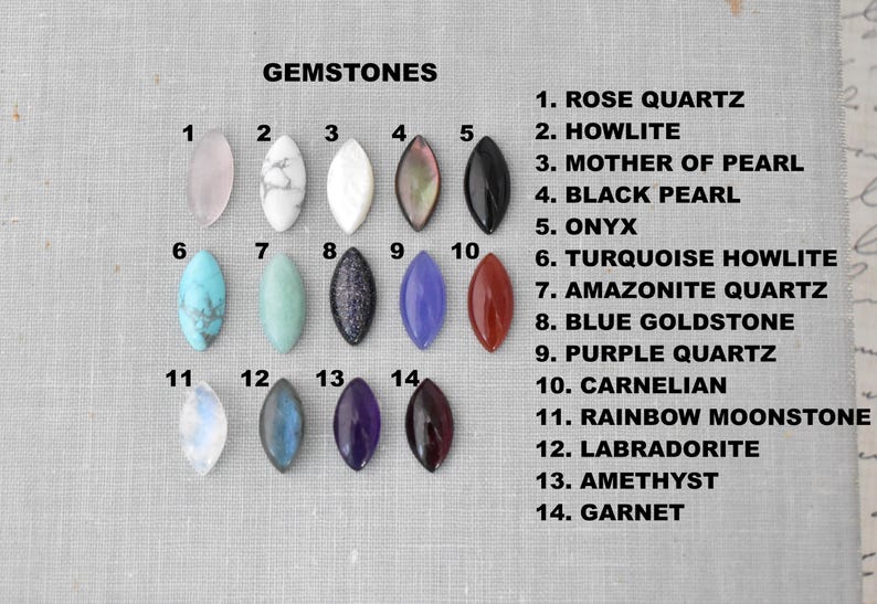 May include: A collection of 14 gemstone cabochons in various colors and textures, including rose quartz, onyx, and amethyst. Each stone is oval-shaped and displayed against a neutral background. The gemstones are labeled with their names.