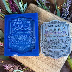 May include: A blue silicone mold and a finished resin piece with an apothecary theme. The mold is a mirror image of the finished product. The resin piece has the text "OLDE SALEM APOTHECARY" and "POTIONS, TONICS, ELIXIRS".