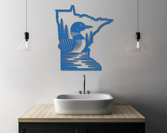 May include: A blue metal wall art piece depicting the state of Minnesota with a loon, trees, and water. The loon is detailed with textured patterns. The artwork is mounted on a white wall above a sink.