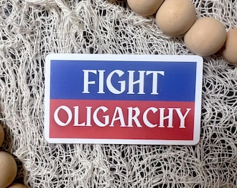 May include: A white sticker with blue and red stripes. The sticker says "FIGHT OLIGARCHY" in white letters.