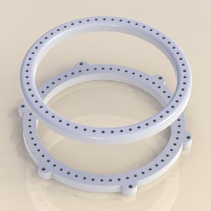 May include: Two light blue, circular objects with evenly spaced holes around the perimeter. The objects are stacked, with one slightly above the other. Each object has four small, rounded protrusions.