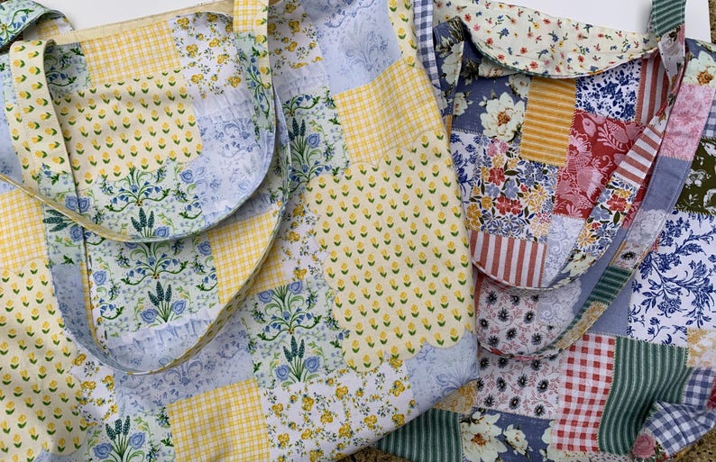 May include: Two patchwork tote bags with floral and geometric patterns. One bag features yellow gingham and floral prints, while the other showcases a mix of floral, striped, and checkered fabrics. Both bags have matching straps.