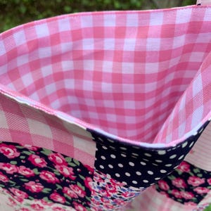 May include: A patchwork tote bag with a pink gingham interior. The exterior features a mix of floral, polka dot, and gingham patterns in shades of pink, navy, and white. The bag's handle is a pink polka dot fabric.